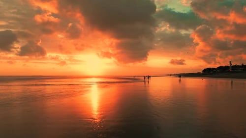 Breathtaking Bali Sunset Over a Tranquil Beach with Silhouetted Figures and Vibrant Skies