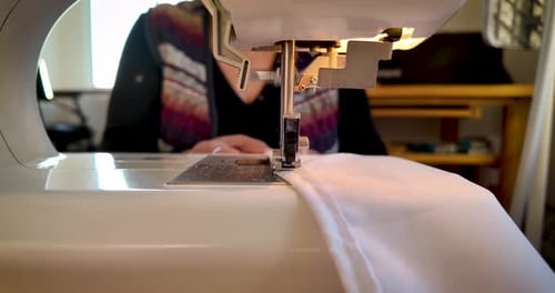 Close-Up of Sewing Finishing White Fabric Guided by Woman’s Hand