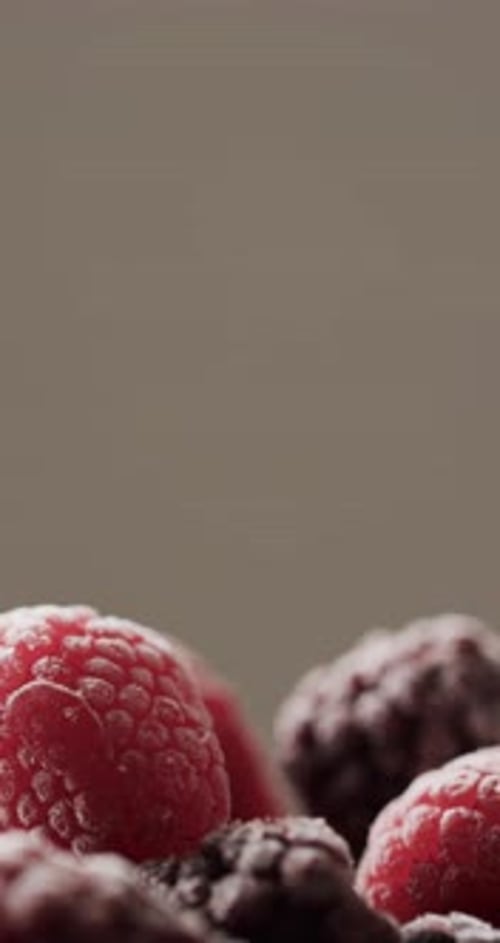 Micro vertical video close up of raspberries and copy space on grey background