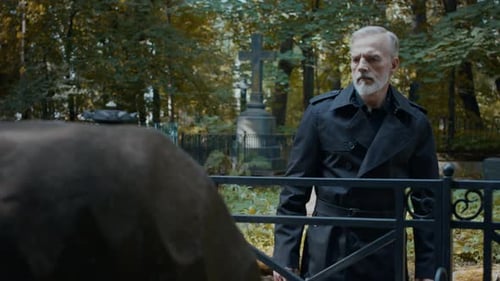 Mid-Aged Man Looking Sadly at Grave in Cemetery