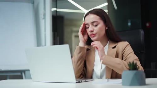 Woman With Headache at Desk in Office