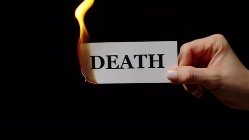 Hand Holding Small Rectangular Paper in Fire with Word Death
