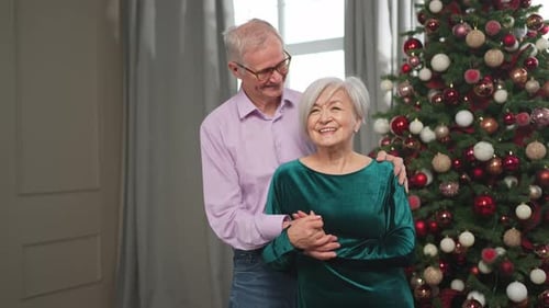Senior Couple Embraces Near Christmas Tree