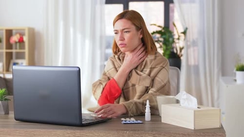 Woman with cold works on laptop at home