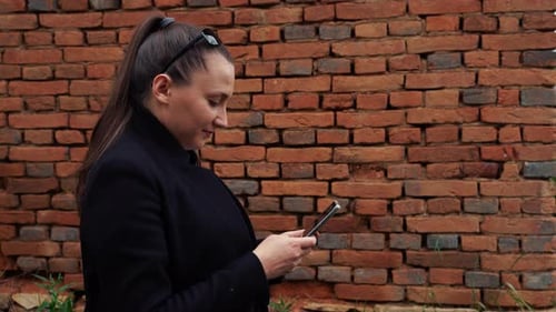 A young woman is scrolling on social media, near an abandoned barn