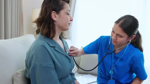Nurse Examines Patient with Stethoscope in Home