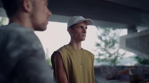 Relaxed friends talking together enjoying summer day in skateboarding park