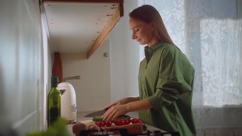 Woman Slicing Cucumber in Sunny Kitchen