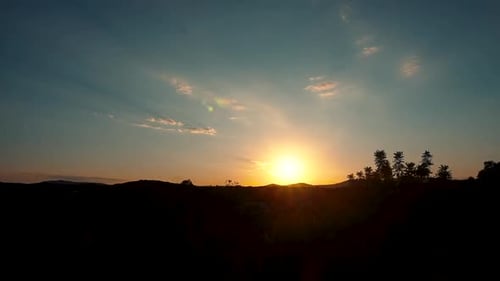 Wolken bei Sonnenuntergang bewegen sich über die Silhouette der Berge und der Wind weht durch das Laub in der Wildnis von Spa