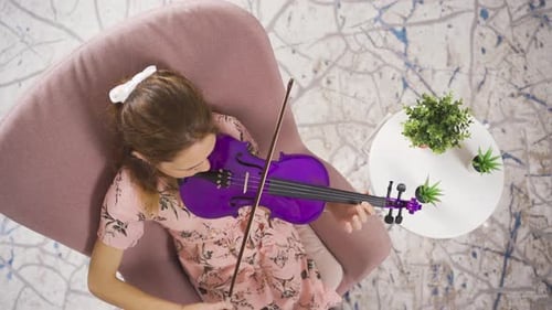 Girl Plays Purple Violin in Armchair