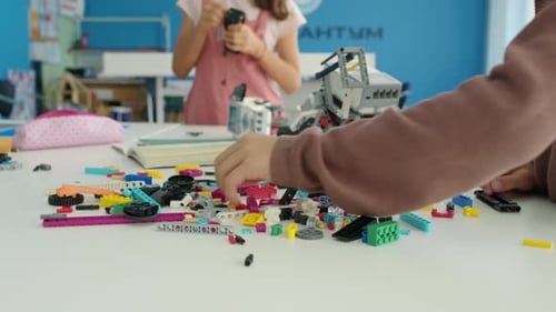 Manos de niños que fabrican robots con bloques de plástico en Hobby Club