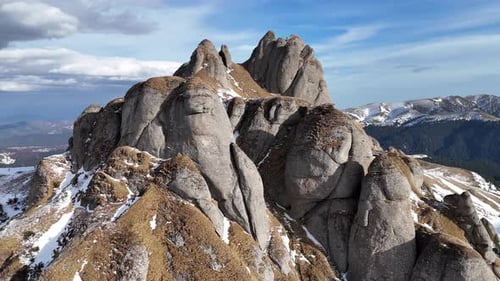 Picos nevados de las montañas de Ciucas bajo un cielo azul, rocas irregulares de cerca, toma aérea
