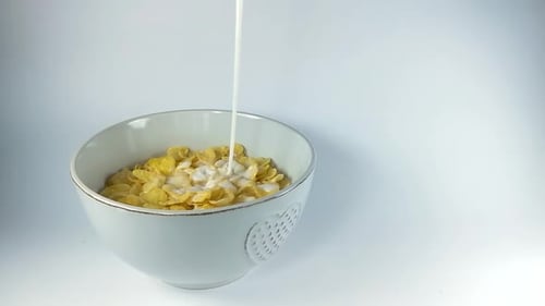 Pouring milk on corn flakes in a ceramic bowl, ISOLATED, STILL, SLOMO