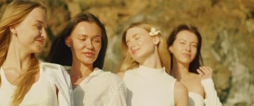Four women outdoors standing in a line all smiling and looking at each other with a rocky background