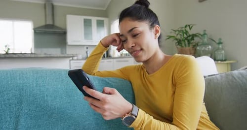 Woman Relaxing on Couch Uses Smartphone