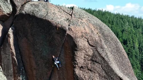 Rock Climber Ascending Steep Mountain Cliff Face