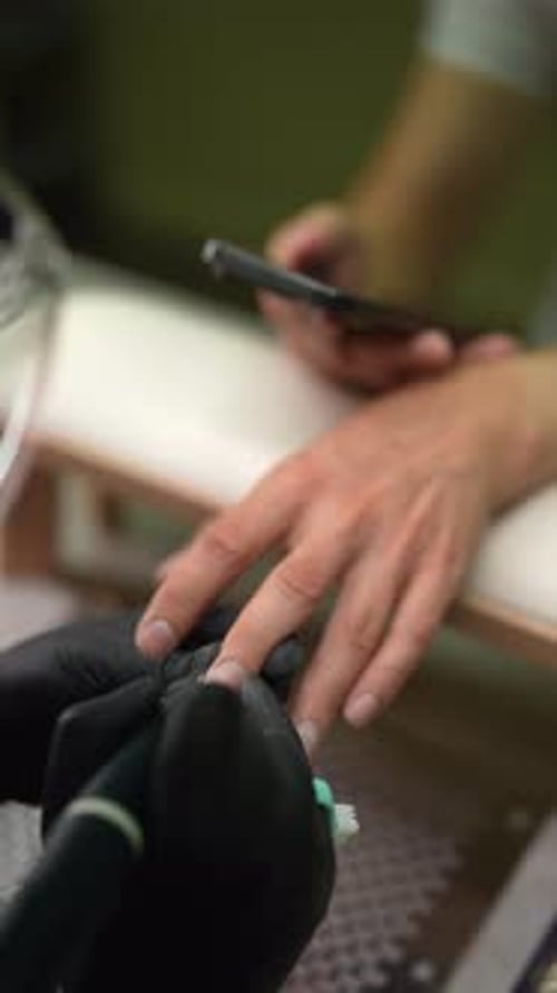 Vertical Highangle View of Manicurist Giving Man Manicure Cleaning Cuticle of Nail Using Electric