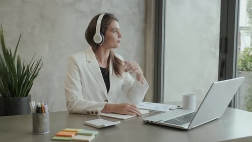 Jeune femme portant des écouteurs et des tenues formelles communiquant et prenant des notes