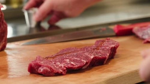 Raw steak getting seasoned with oil and spices