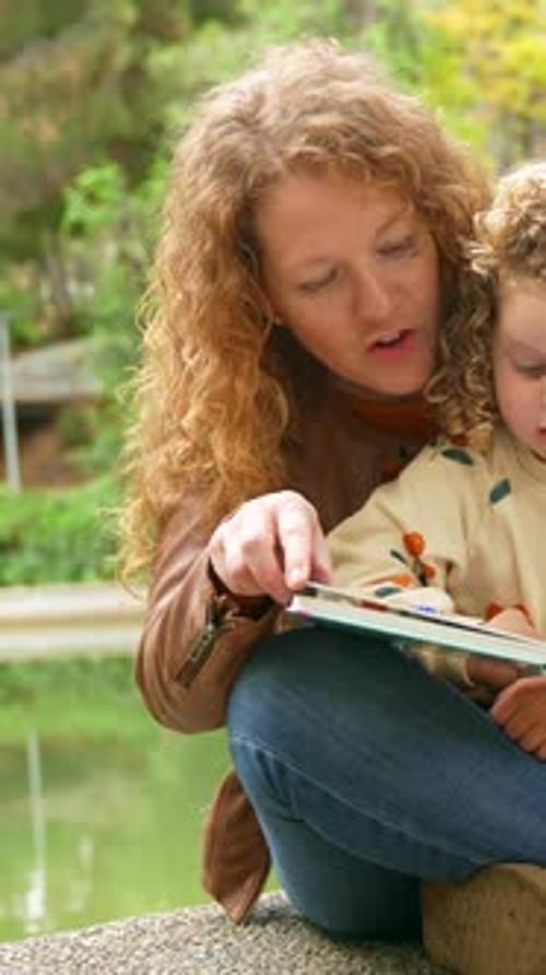 School Girl and Mother Reading a Book in a Park