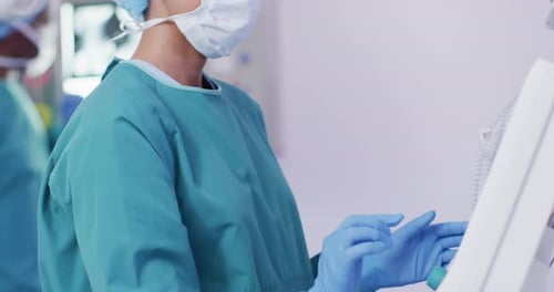 Video of biracial female surgical assistant preparing electronic equipment in operating theatre