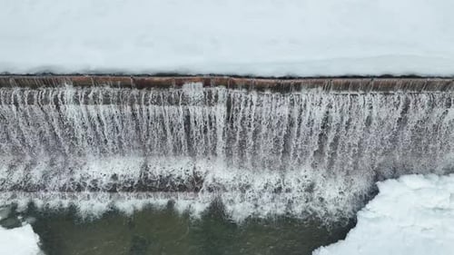 Drone Moving from Right to Left Over Winter Dam, Water Flow and Ice Formation
