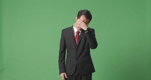 An Asian Business Man Having Headache While Standing In Front Of Green Screen