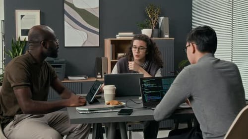Three Young IT Specialists Discussing Development of New Software Product