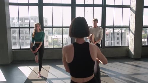 Yoga Instructor Leads Three Young Adults in Loft