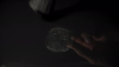 A white fingerprint on a black glass, I am cleaning it with a brush.