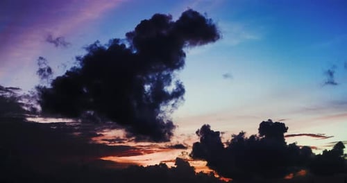 Dark clouds moving and yellow orange reflections on the blue sky after sunset. Time Lapse