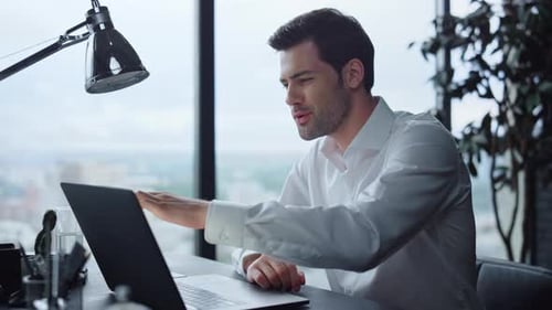 Smiling businessman enjoys victory after good news in office video call