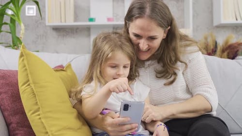 Mother and Child Using Smartphone on Sofa