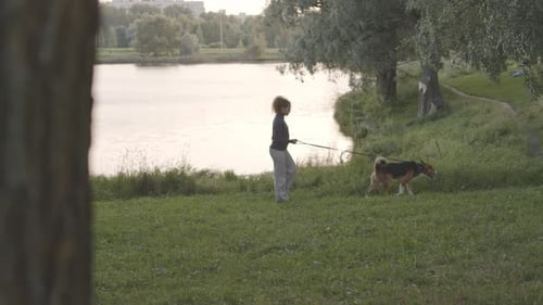 Woman with Dog Walking beside River in Forest