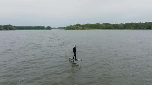 athlete on hydro sup foil surf in wave on a river filmed with drone in front of close up