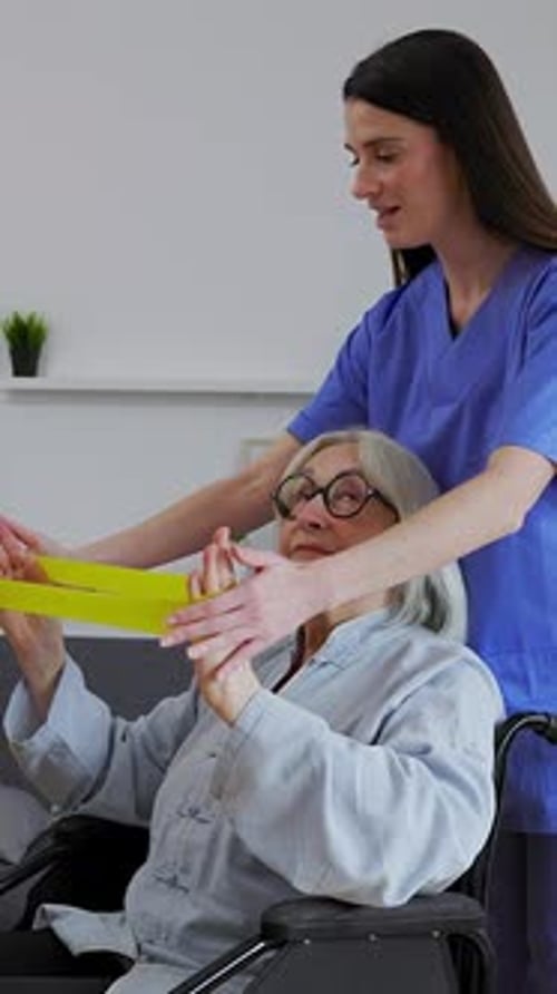 Caregiver Helping Senior Woman with Resistance Band Exercise