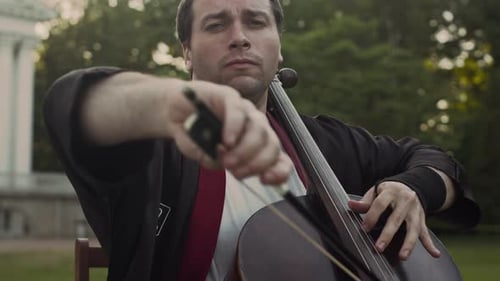Young Adult Plays Cello in Green Space