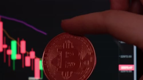 Weibliche Hand hält Bitcoin-Goldmünze auf dem Hintergrund des Börsendiagramms Bitcoin-Mining-Handel