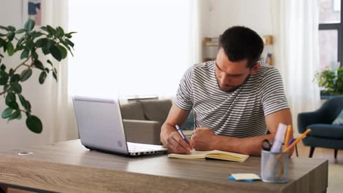 Young hispanic man working remotely from home office with laptop and notebook
