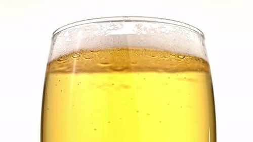 A glass of beer is filled with bubbles and foam
