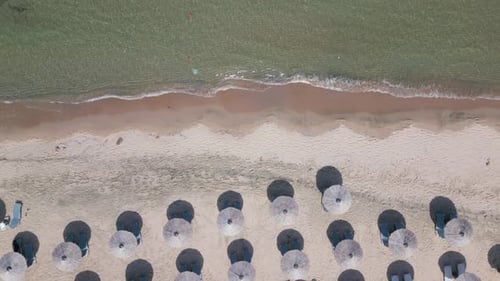 Aerial View of an Amazing Empty Sand Beach with Straw Beach Umbrellas and Turquoise Clear Water