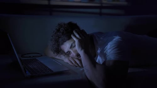 Young Adult Lying on Couch Yawning at Night