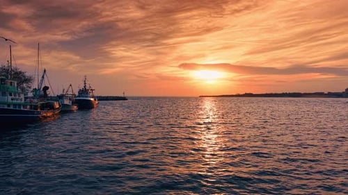 Boote legten bei Sonnenuntergang über Wasser mit bewölktem Himmel am Hafen an.