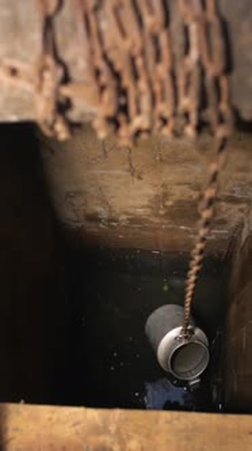 Vertical Process of Raising Water From a Village Well with a Bucket on a Chain