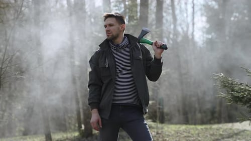Porträt eines mutigen selbstbewussten Mannes mit Axt auf der Schulter im Wald
