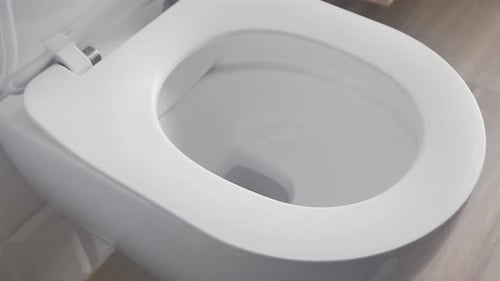 Öffnen Sie den Toilettendeckel und heben Sie den Toilettensitz an. Hygiene beim Toilettengang.