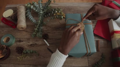 Hands Tying Gift Tag on Christmas Present