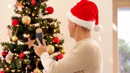 Man in Santa Hat Video Calling by Christmas Tree