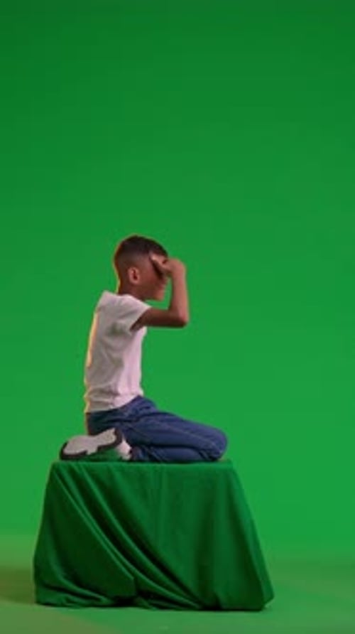 A Schoolboy Gazes Into the Distance at the Green Screen