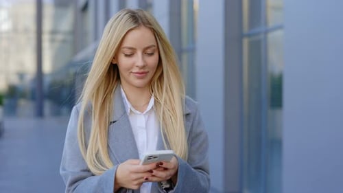 Woman Walking and Using Mobile Phone in City